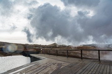 Geothermal area in Iceland. Powerful steam jet above the ground. A smoking geyser on a background of yellow clay and a cloudy sky. Reykjanes Peninsula