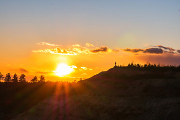 The man spread his hands to the sides towards the sun. Active outdoor recreation. The winner at the top of the mountain is looking at dawn.