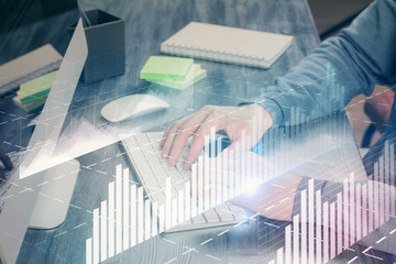 Stock graph with businessman typing on computer in office on background. Concept of analysis. Double exposure.