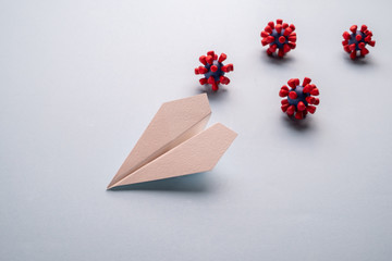 Concept of fly danger. Paper plane and models of covid-19 virus on blue background