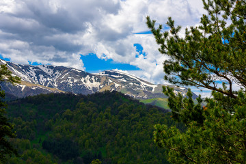 Beautiful mountain panorama with lush greens, blue skies, and puffy clouds