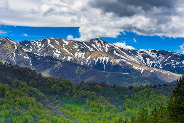 Beautiful mountain panorama with lush greens, blue skies, and puffy clouds