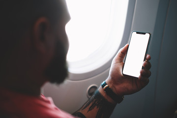 Crop passenger watching smartphone traveling on plane