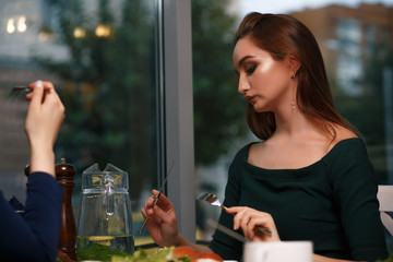 Two young successful women are having dinner in a restaurant and talking