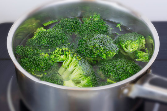 Cooking organic broccoli florets in small stainless steel pan in domestic kitchen.Vegan meal preparation.Healthy eating.Popular green vegetable.Healthy diet and lifestyle.