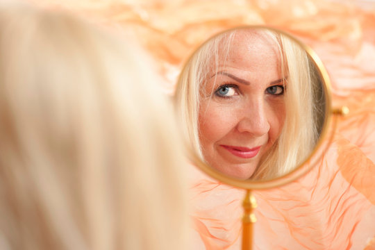 Woman With Magnifying Mirror On Orange