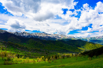 Beautiful mountain panorama with lush greens, blue skies, and puffy clouds