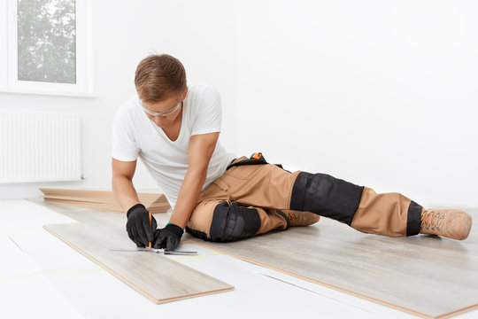 Flooring services - laminate installation in a floating way. Carpenter worker installing laminate flooring in the room