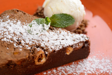 brownies sprinkled with slices of almonds and mint, stacked against an orange plate.