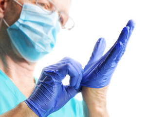 Doctor in medical mask putting on blue gloves isolated on white