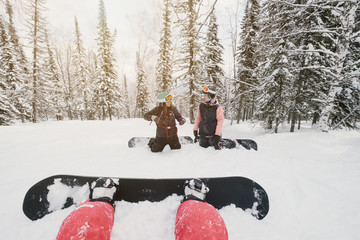 snowboarders female seating and rest in winter snow-covered spruce forest, fresh snow powder,...