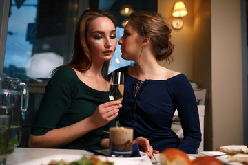 Two girls gossip in a cafe in the evening