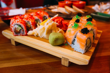 sushi restaurant menu, delicious japanese traditional seafood. gourmet maki roll with tamago omelet, chuka and cream cheese, covered with salmon, served on red plate, close up
