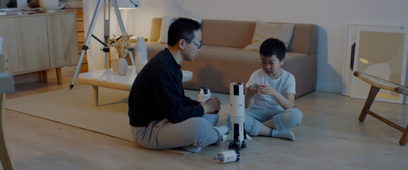 Chinese father and son playing together, building moon landing mission rocket together. Stay home,...
