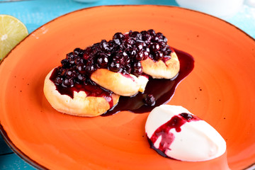 Cottage cheese pancakes with currant on a plate