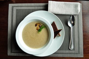 Cream of porcini mushroom soup with cream and croutons in white bowl. Top view.