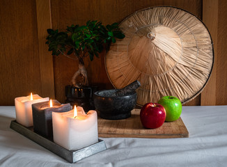 Composition of wellness concept with red and green apple, candles, asian hat, a bonsai, and wood background.