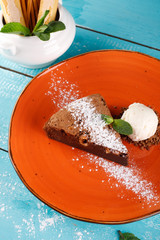 brownies sprinkled with slices of almonds and mint, stacked against an orange plate.