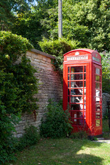 Bibury (England), UK - August 05, 2015: A red phone box in Bibury village, Gloucestershire, England, United Kingdom.