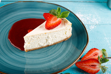 Cheesecake with strawberries on a blue plate