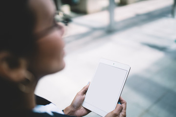 Unrecognizable spectacled woman browsing tablet in city