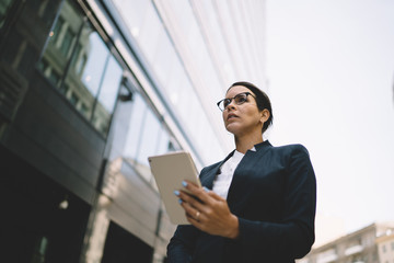 Thoughtful businesswoman watching tablet in urban street
