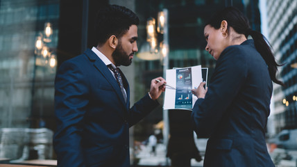 Confident ethnic expert giving advice to pensive adult businesswoman in office