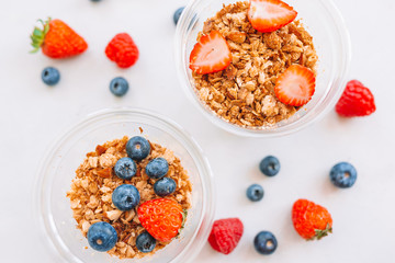 Oatmeal porridge in bowl topped with fresh blueberries, cranberries and homemade crunchy granola