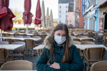 Woman with medical mask in empty cafe terrace