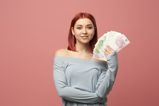 Happy woman holding euro banknotes in hands while standing in studio