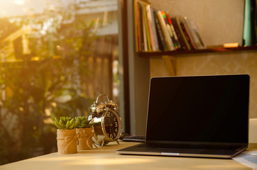 Naklejka na ściany i meble (Clipping path) Work desk in home office with laptop/notebook computer, clock, calculator, report paper, cactus tree and cup of coffee in morning. Work hours & lifestyle business. Work from home.