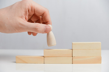 Career growth concept. Hand holds wooden blocks on a white background.