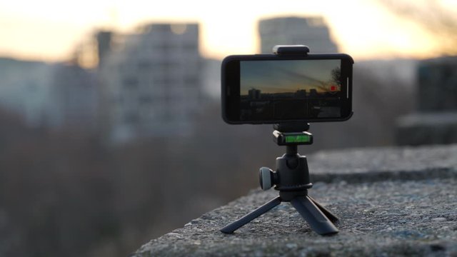 Using mobile phone to record video, capture city scene with video camera app, phone screen closeup rack focus.
