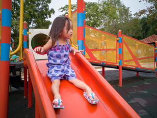 Toddler girl playing on a slide at a playground