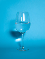 The glass is half filled with water. A glass of water is standing on a gulb background. Healthy food concept