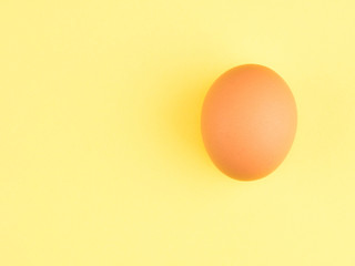 One brown chicken egg on a yellow background. Healthy eating concept