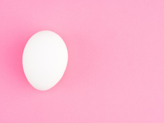One white chicken egg on a pink background with copy space. Healthy eating concept