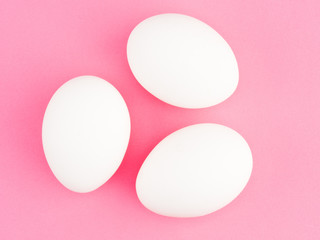 Three white chicken egg on a pink background. Healthy eating concept