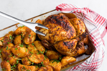 Baked whole chicken with potatoes and herbs in a rustic style. Top view, side view on a light background. Close-up and medium plan. Space for text.