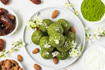 Homemade raw energy balls made of green matcha tea, dates and nuts with spring flowers. Top view. Food styling