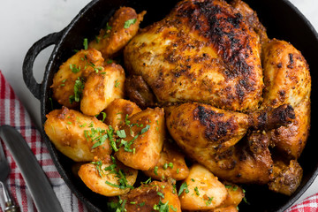 Baked whole chicken with potatoes and herbs in a rustic style. Top view, side view on a light background. Close-up and medium plan. Space for text.