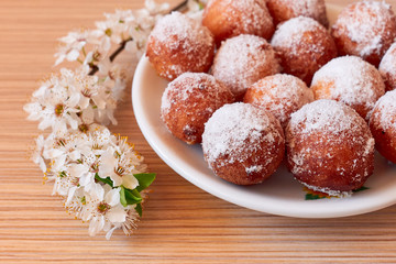 Homemade donut holes with a blooming brach on desk , during pandemic isolation