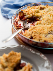 Traditional British Red berry crumble in glass baking dish with cloth on white background. Close up. Delicious dessert in rustic style, selective focus