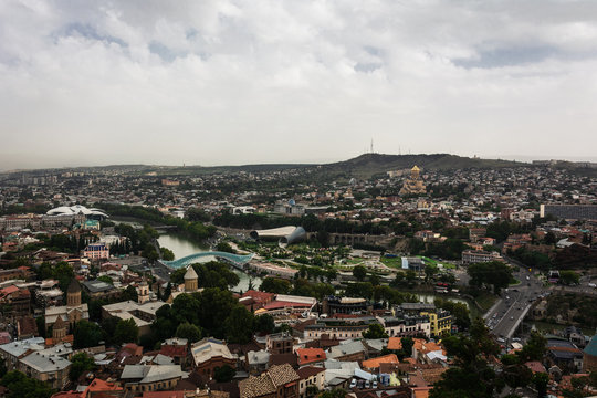 Beautiful landscape view of Old Town Tbilisi with Bridge of Peace and Holy Trinitity Cathedral in cloudy day, Georgia.