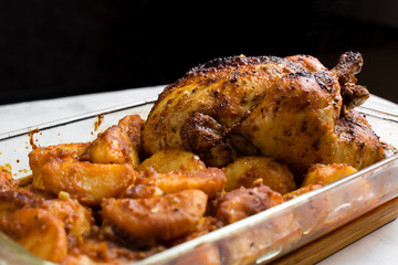 Baked whole chicken with potatoes and herbs in a rustic style. Top view, side view on a light background. Close-up and medium plan. Space for text.