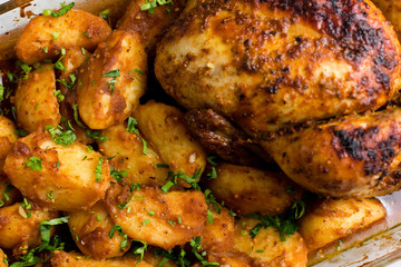 Baked whole chicken with potatoes and herbs in a rustic style. Top view, side view on a light background. Close-up and medium plan. Space for text.