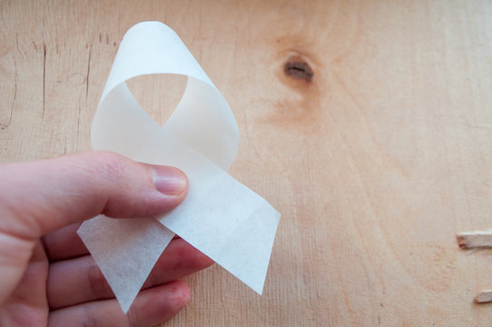 In hand is a white ribbon of awareness. World Alzheimer's Day. World Parkinson's Day. World Suicide Prevention Day, International Day for the Elimination of Violence against Women - Powered by Adobe