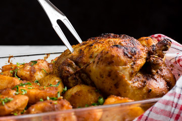 Baked whole chicken with potatoes and herbs in a rustic style. Top view, side view on a light background. Close-up and medium plan. Space for text.