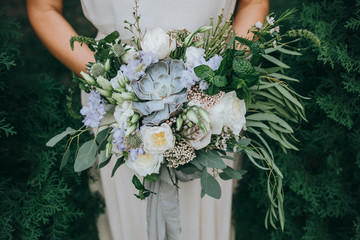 Bridal bouquet. Wedding. The girl in a white dress sitting on a wooden chair and holding a...