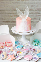 Mermaid theme candy bar with cake, cupcakes, macaroons and biscuits. Sea shell shaped macaroons with pearls.